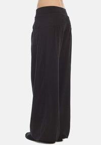 Black wide-leg trousers with a fitted waistband, made from soft fabric. Features a flowy design and side pockets, suitable for casual wear.