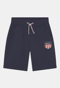 Hosen in Marineblau aus Baumwolle, mit einem Kordelzug mit GANT-Branding, seitlichen Taschen und einem gestickten Logo-Patch mit Streifen.