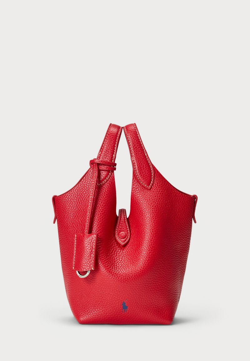 Bolsa de mão em pele vermelha com acabamento texturizado, formato curvado, alças superiores duplas e uma pequena etiqueta decorativa destacável. Apresenta logo em azul.