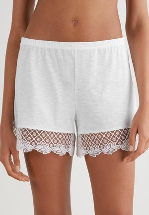 Witte katoenen shorts met een textuur kant zoom. Het kant heeft een bloemmotief en gegolfde randen, wat detail toevoegt aan het eenvoudige ontwerp.