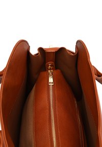Wnętrze brązowej skórzanej torebki wyposażone jest w strukturalne podszewki, kieszeń na zamek błyskawiczny oraz gładką, otwartą komorę. Złote akcenty z metaloplastyki.