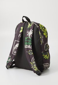 Mochila negra y morada con estampados florales, correas ajustables, un asa superior y acentos de marca. El material parece duradero.