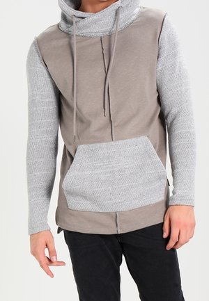 Sudadera con capucha que presenta una mezcla de tejidos en gris claro y topo, con mangas grises texturizadas y un bolsillo frontal. Diseño casual y ajustado.
