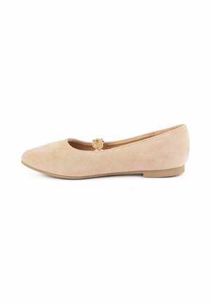 Zapato plano de ante beige con un pequeño broche decorativo dorado en la parte superior y un tacón bajo y plano sobre un fondo blanco.