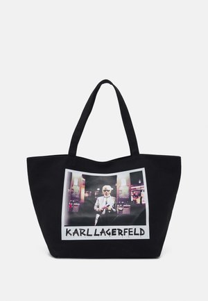 Sac fourre-tout en toile noire avec une grande impression graphique représentant une silhouette. Le texte "KARL LAGERFELD" apparaît sous l'image.