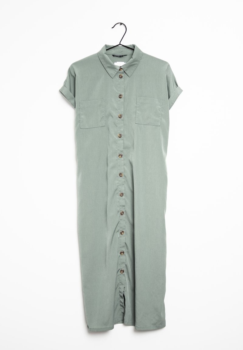 Robe vert clair à manches courtes, boutonnée, avec col et deux poches poitrine, suspendue sur un cintre noir.