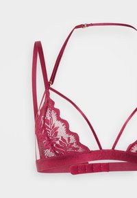 Μπορντώ δαντελένιο σουτιέν με λουλουδάτο μοτίβο, οδοντωτές άκρες και ρυθμιζόμενους σατέν ιμάντες. Διαθέτει κλείσιμο με κόπιτσα στο πίσω μέρος για ασφαλή εφαρμογή.