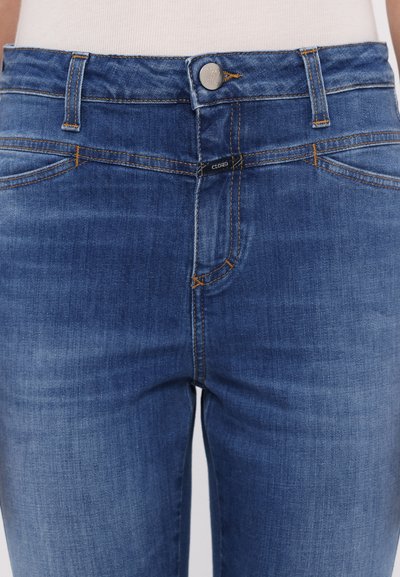 Jeans i mørkeblå denim med en jevn tekstur, med høy midje, knappelukking og kontrasterende oransje søm.