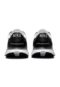 Črno-bele Nike superge z gladkim zgornjim delom, podloženo ovratnikom in teksturiranim podplatom, ki nosi blagovno znamko na peti.