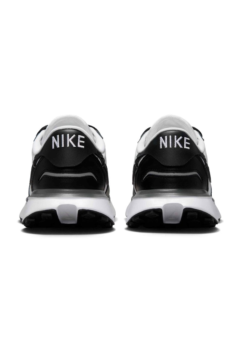 Zapatillas Nike en blanco y negro con parte superior lisa, collar acolchado y suela texturizada con marca en el talón.