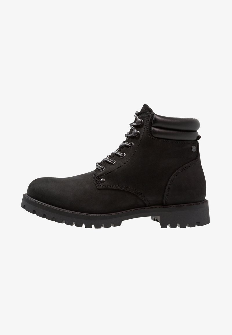Botte de randonnée en cuir noir avec col rembourré à la cheville, œillets métalliques, semelle épaisse à crampons et fermeture à lacets sur le devant, vue de profil.