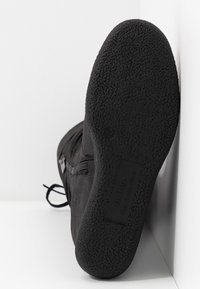 Botte en daim noir avec une semelle en caoutchouc texturée, dotée d'une fermeture éclair latérale et de lacets, posée sur un fond blanc. Taille 37 indiquée.