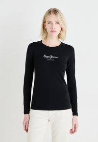 Crna majica dugih rukava od pamuka, s bijelim logotipom "Pepe Jeans London" na prsima. Jednostavan dizajn s okruglim izrezom.