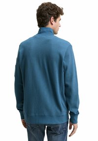 Blauwe, textuurrijke pullover met een hoge kraag en geribde manchetten, met een ontspannen pasvorm en een subtiele patroon op de stof.