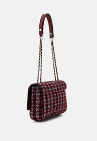 Textured woven handbag in red and navy with a fold-over flap, chain strap, and leather handle; features a checkered pattern.