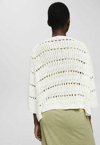 Top blanco de punto con un diseño de tejido abierto, de corte holgado, mangas cortas y dobladillo recto. Patrón texturizado con aberturas superpuestas en toda la prenda.