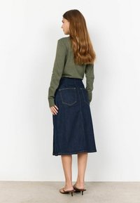 Fustă midi din denim de culoare albastru închis, cu croi drept, slit lateral și buzunare pe spate; asortată cu un top lung cu mânecă de culoare verde măslin.