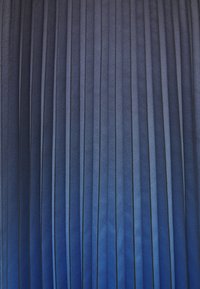 Tissu plissé en dégradé de nuances de bleu, présentant des lignes verticales avec des textures variées et un léger éclat, créant de la profondeur et un intérêt visuel.