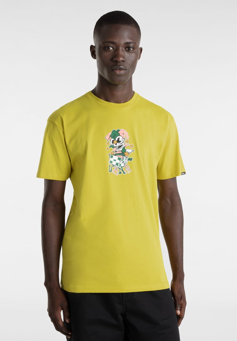 Camiseta de algodón amarilla de manga corta, con un diseño gráfico divertido de un cráneo con un sombrero de bufón, sobre un fondo simple.
