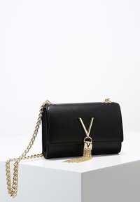 Svart läder axelväska med guld-tonad kedjesnöre, med ett V-format lås och dekorerad med en tofs. Rektangulär form, slät textur.