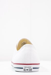 Baskets en toile blanches avec semelle en caoutchouc, design basse et accents rayés rouges et bleus. Logo visible sur le talon.