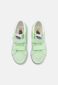 Zapatillas de ante verde con correas de velcro, acentos blancos, puntera perforada y logotipo negro contrastante en la lengüeta. Forma de punta redondeada.