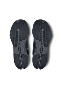 Semelles de chaussures de sport noires en caoutchouc texturé avec un motif en nid d'abeille, une rainure centrale pour la flexibilité et une zone de renfort à l'avant.