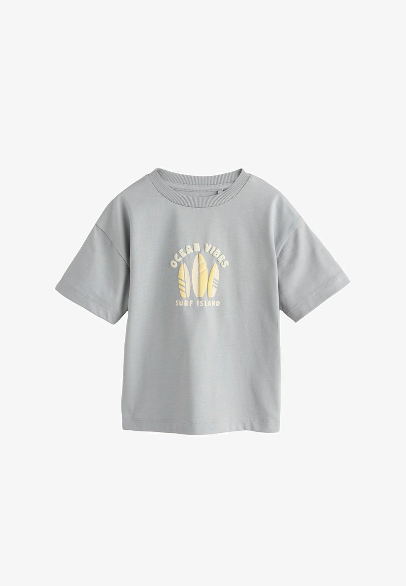 T-shirt gris clair à manches courtes avec col rond, présentant trois illustrations de planches de surf jaunes et le texte "OCEAN VIBES SURF ISLAND" sur le devant.