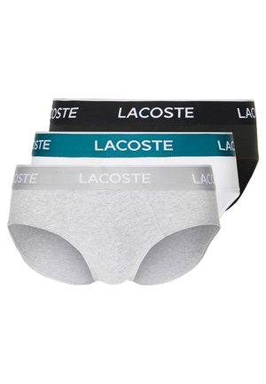 Tri páry pánskych slipov v sivej, čiernej a tyrkysovej farbe, s kontrastnými elastickými pásmi s logom "LACOSTE" v bielej farbe. Mäkko uvedený materiál z bavlny.