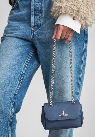 Μικρή μπλε τσάντα χρώματος ναυτικού από υλικό με υφή, με ασημένια αλυσίδα και μεταλλικό λογότυπο στην μπροστινή καπάκι.