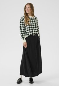 Black maxi skirt paired with a cream and black houndstooth patterned sweater. The outfit features a silver-tone belt and black loafers.