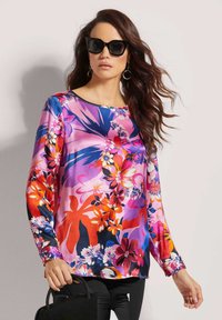 Langärmlige Bluse mit einem lebhaften Blumenmuster in Pink, Rot und Blau auf einem glatten Stoff, mit Rundhalsausschnitt und gefütterten Ärmeln.