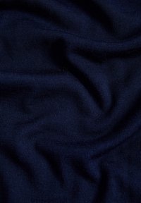 Marineblau gestrickter Stoff, glatte Textur mit einem subtilen Rippenmuster, das sanfte Falten und Drapierungen zeigt. Kompakte Webart, weiches Aussehen.