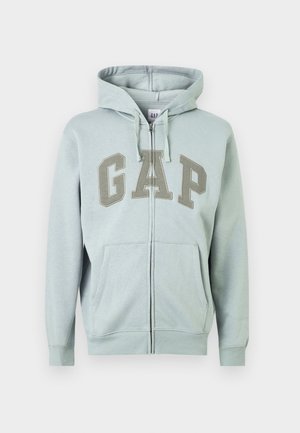 Light gray zip-up hoodie with front pockets, drawstring hood, and "GAP" embroidered in large letters across the chest.