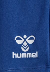 Blå tyg med en slät textur pryds av en vit logotyp föreställande ett stiliserat bi och ordet "hummel" under.