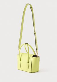 Μικρή δομημένη τσάντα χειρός από δέρμα σε φωτεινό πράσινο χρώμα με διπλές κορυφαίες λαβές και ρυθμιζόμενο λουρί ώμου σε λευκό φόντο.