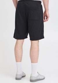 Mustad puuvillasegust püksid, millel on elastne vöökoht ja tagatasku. Stiiliks hallid tossud ja valged sokid.