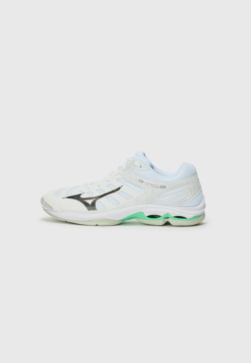 Chaussure de sport blanche avec un dessus en maille, accents gris et semelle extérieure verte. Présente un logo noir proéminent et des motifs texturés sur le côté.
