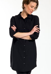 Zwarte, lange mouwen knoopshirt met een kraag, enkele borstzak en afgeronde zoom. Glad textuur, lichte stof.