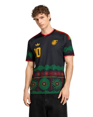 Joven con una camiseta negra con patrones en rojo, verde y amarillo, número 10 y un escudo de Jamaica en el pecho.