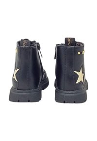 Stivali neri in pelle fino alla caviglia con un design a stella dorata e borchie decorative sul tacco. Presentano una chiusura con zip e suola in gomma testurizzata.