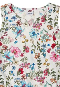 Blouse blanche sans manches avec un imprimé floral coloré, comprenant des fleurs roses, bleues, rouges et jaunes ainsi que des feuilles vertes. L'étiquette indique "CECIL."