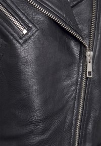 Black leather jacket with a textured finish, featuring a diagonal zipper and silver hardware. Accents include a notched collar and zippered pockets.