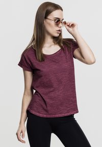Burgundijas krāsa īsām piedurknēm T-krekls viegla auduma ar apaļu kakla izgriezumu un sarullētām piedurknēm, apvienots ar melnām legingām un apaļajām saulesbrillēm.
