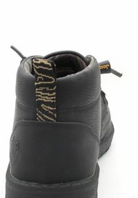 Sneaker nera alta in pelle texturizzata, con un tassello di estrazione a contrasto e suola in gomma. Presenta ulteriori accenti di cucitura.