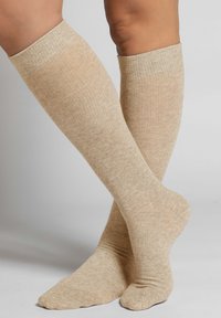 Calze color beige fino al ginocchio con un design a coste, realizzate in materiale morbido, caratterizzate da una texture liscia e una punta e tallone rinforzati.