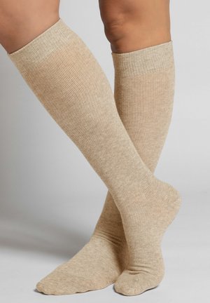 Beige kniekousen met een geribbelde structuur, gemaakt van zacht materiaal, met een gladde textuur en een versterkte teen en hiel.
