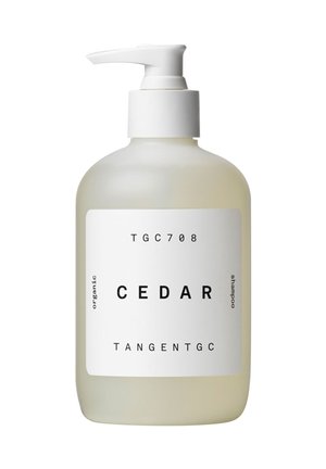 Flacon pompe blanc étiqueté "CEDAR" shampooing biologique par TangentGC, design simple sur un flacon translucide jaune pâle.