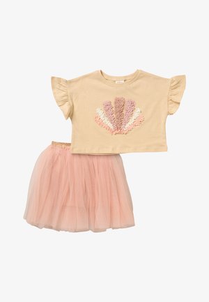 Beżowa bluzka z krótkim rękawem i falbanami na rękawach oraz pastelową aplikacją kwiatową, w zestawie z różową spódnicą tiulową z elastycznym pasem.