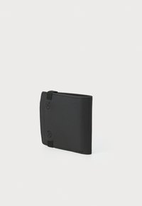 Svart lommebok laget av syntetisk materiale, med et minimalistisk design med synlig søm, et stropp og en glatt tekstur.